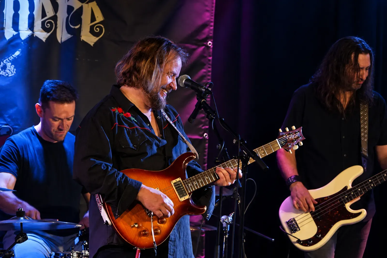 Nerli There på scenen. Mats Nerli synger og spiller gitar i midten, Stian Rekdal bak trommene til venstre og Endre Hindhammer på bass til høyre.